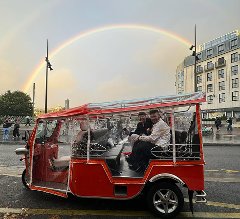 Vue d'un tuktuk avec arc-en-ciel à Paris