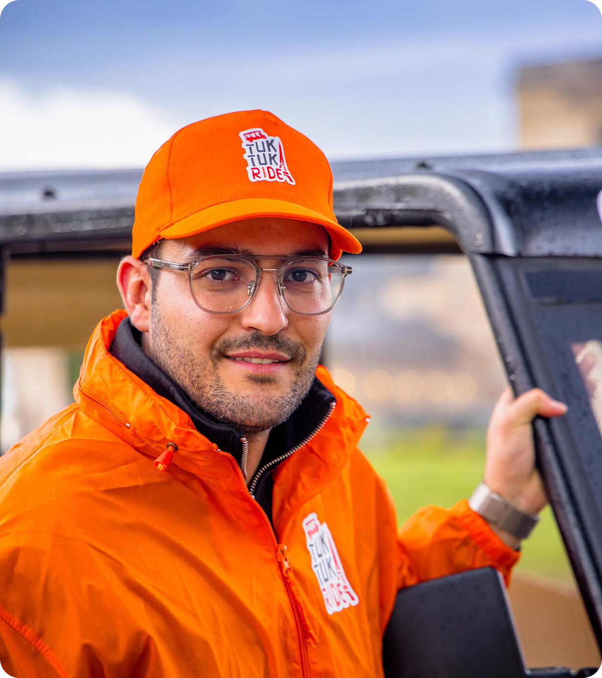 Chauffeur Tuktuk Ride Paris en tenue orange souriant
