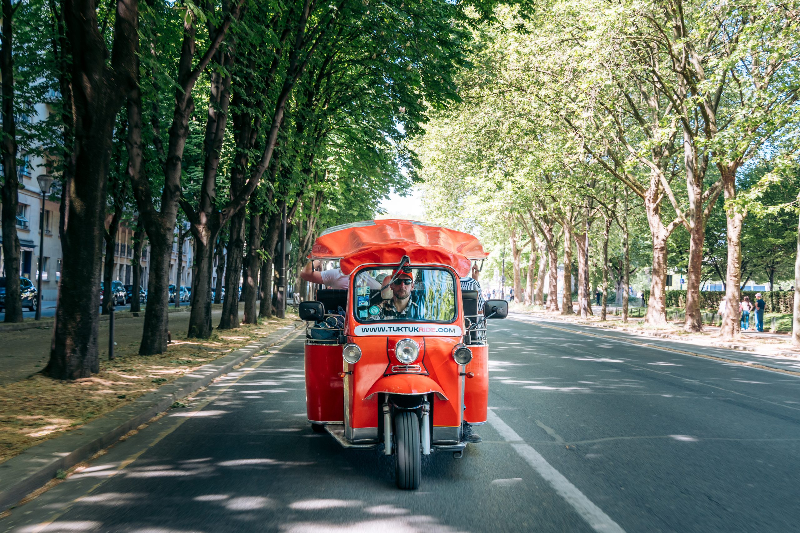 Tuktuk rouge Tuktuk Ride sur une avenue arborée parisienne
