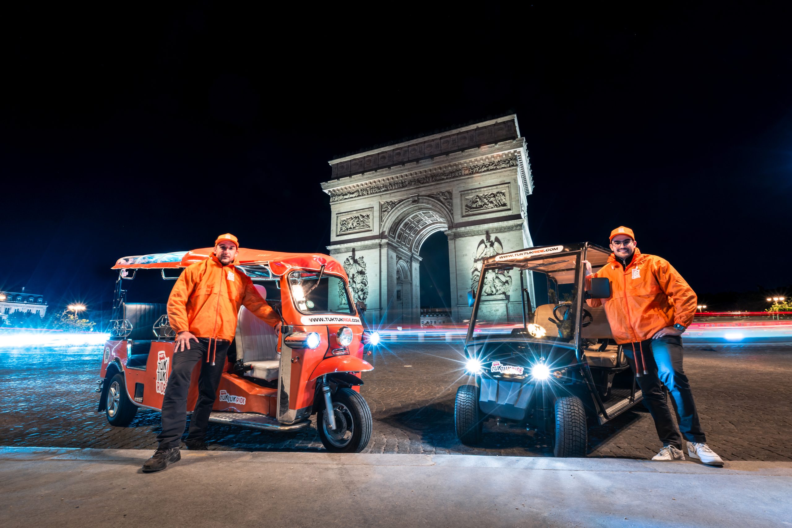 Équipe Tuktuk Ride avec tuktuks devant l'Arc de Triomphe illuminé