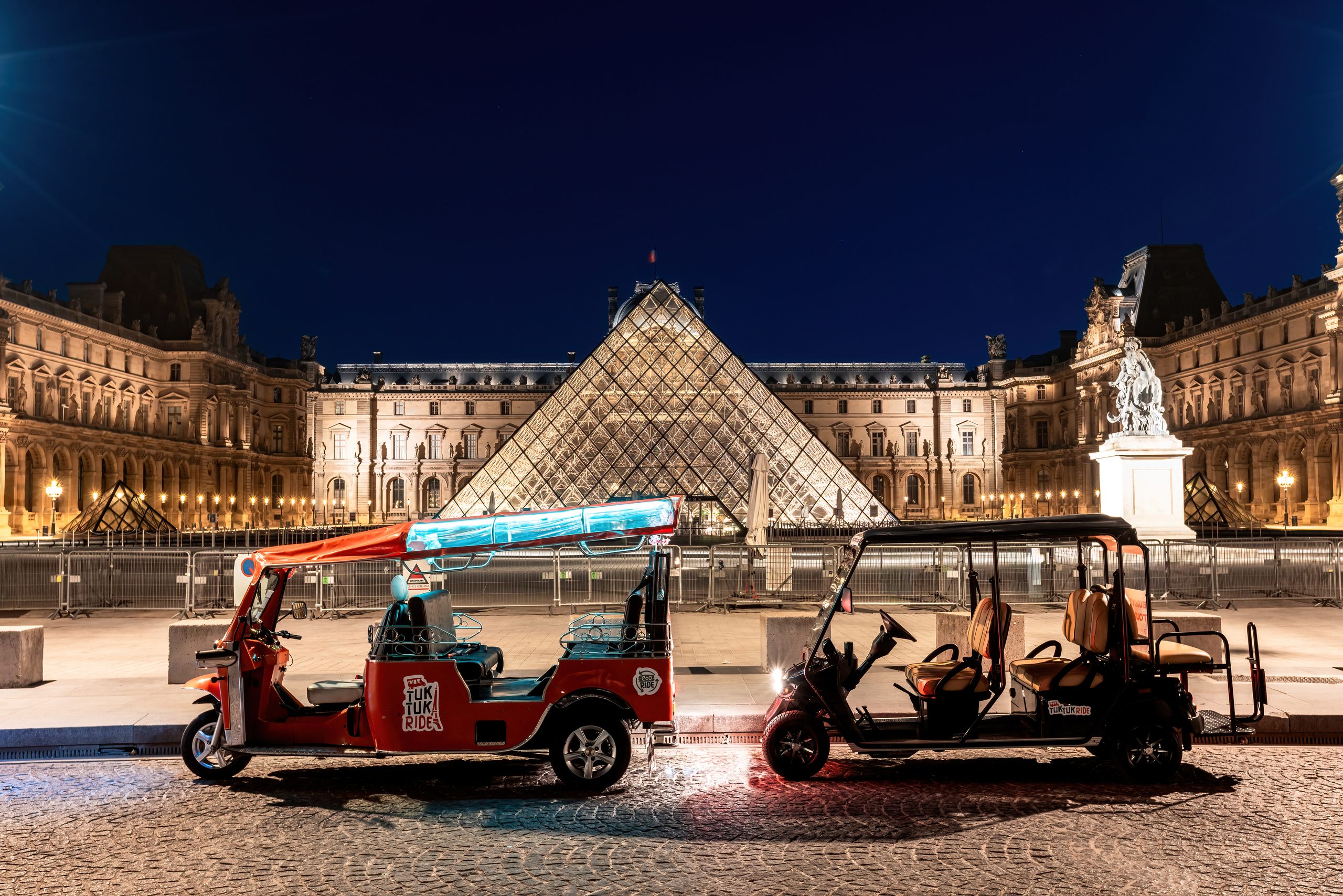Tuktuks orange devant la pyramide du Louvre la nuit