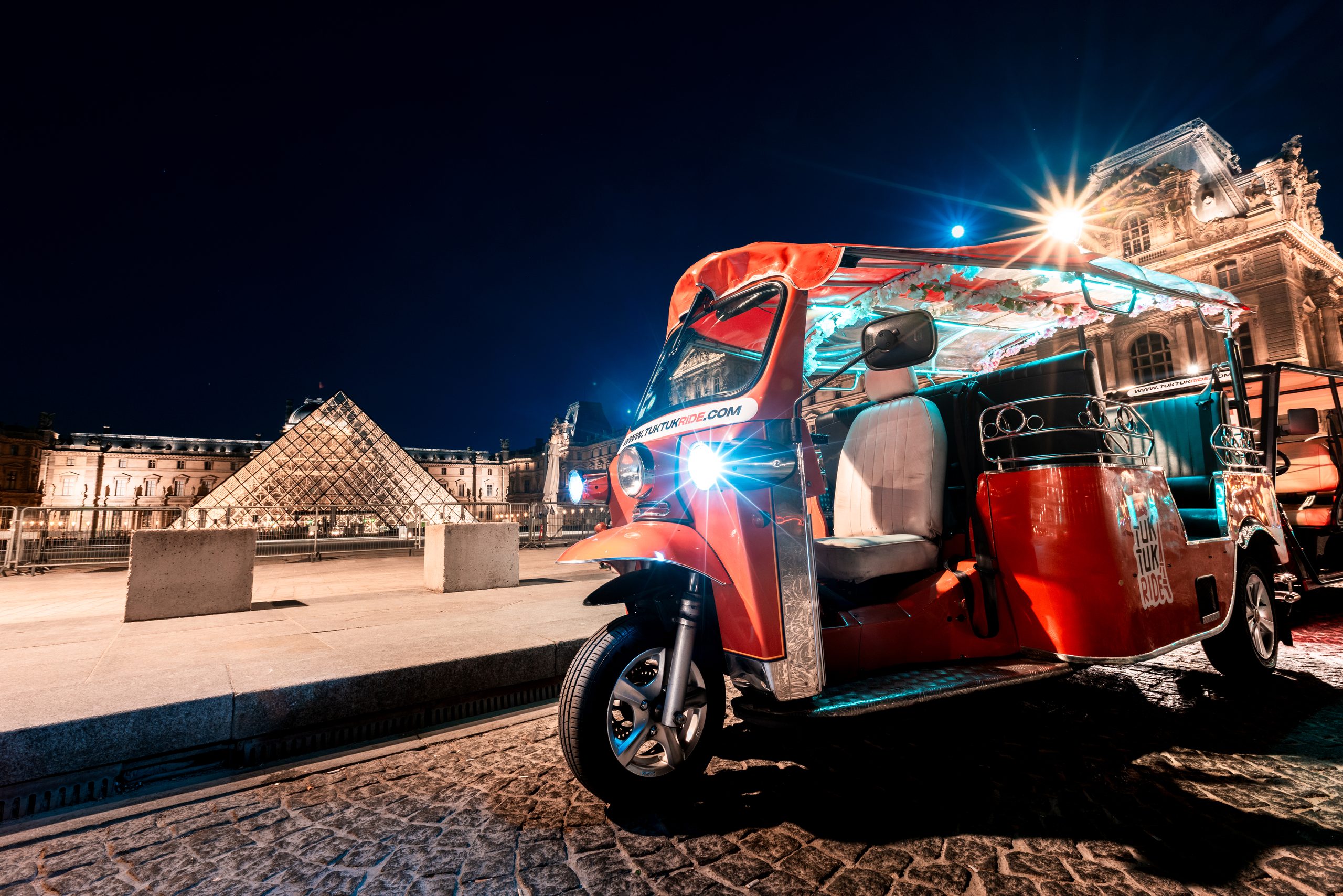 tuktuk devant le louvre à paris de nuit lors d'une visite nocturne de la capitale