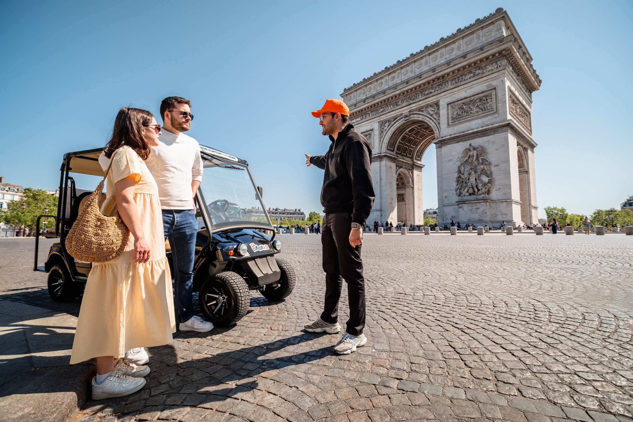Couple and Tuktuk Ride driver in front of the Arc de Triomphe in Paris